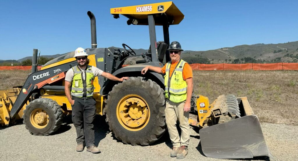 two construction workers with tractor at start of Big Wave housing project in Half Moon Bay